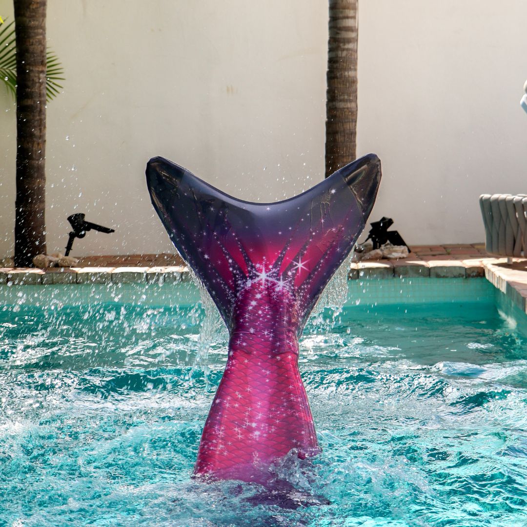 Zwemmer met de Pink Passion zeemeerminset in een helderblauwe zwembad, met een glanzende, roze staart.